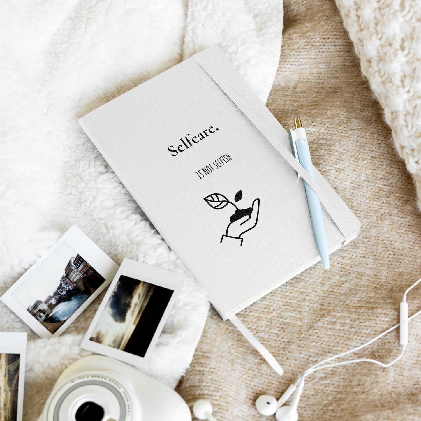 Weißes Notizbuch mit schwarzem Motiv einer Hand, die eine Pflanze hält, und dem Text: „Selfcare, is not selfish“.