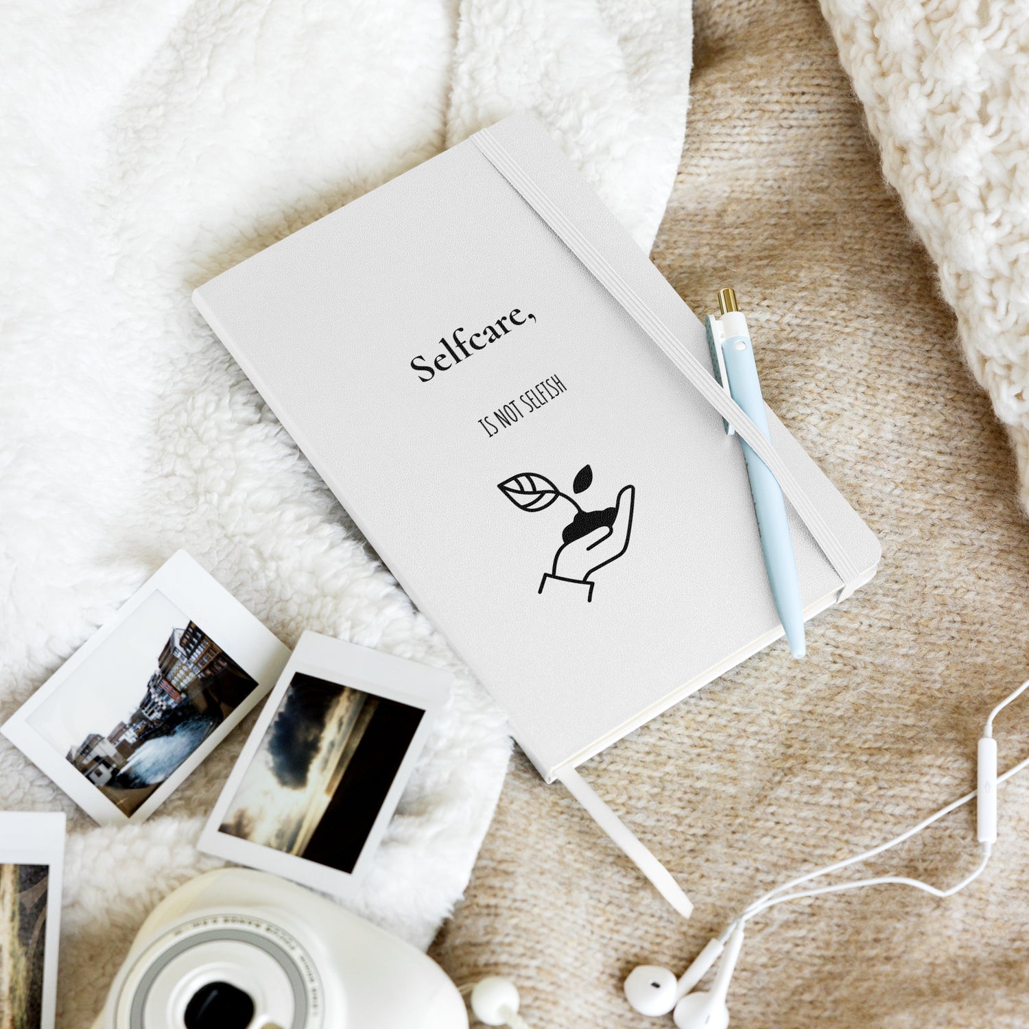 Weißes Notizbuch mit schwarzem Motiv einer Hand, die eine Pflanze hält, und dem Text: „Selfcare, is not selfish“.
