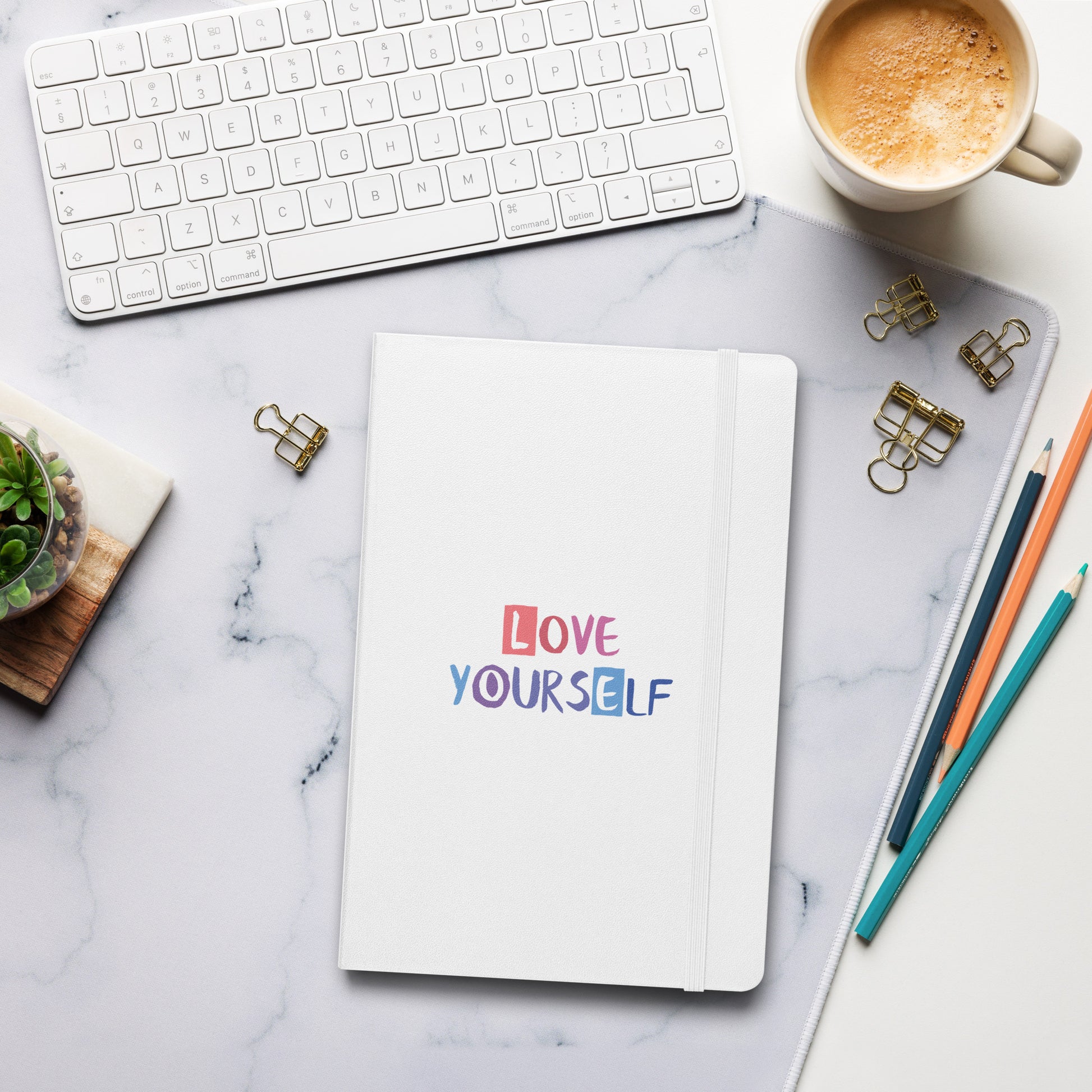White notebook with colorful "Love Yourself" text on the cover.