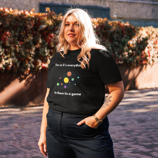 Schwarzes T-Shirt mit Planeten-Motiv und dem Spruch „For us it’s everything, to them it’s a game“.